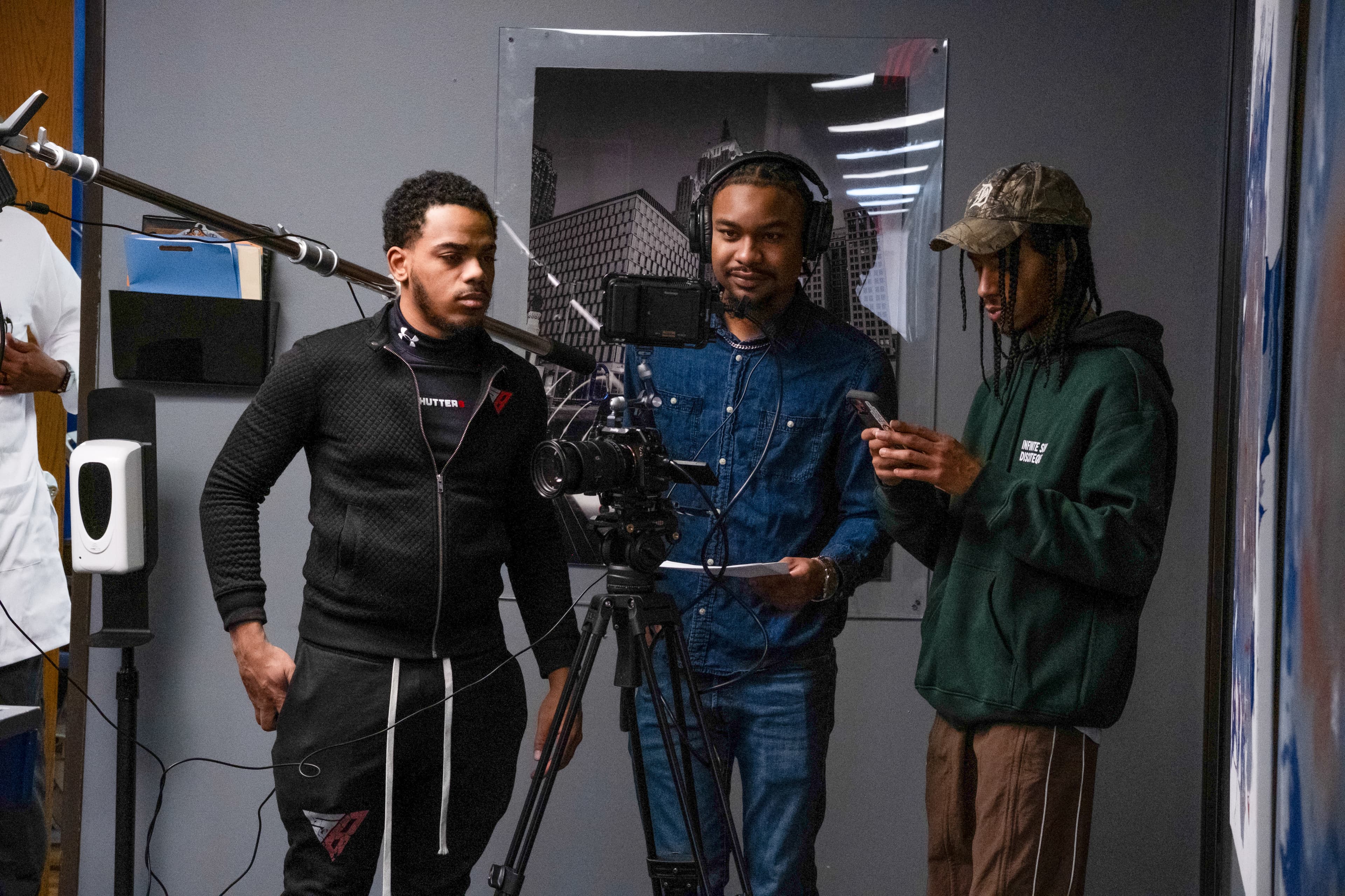 Three men filming in a studio with a professional camera and an overhead boom microphone.