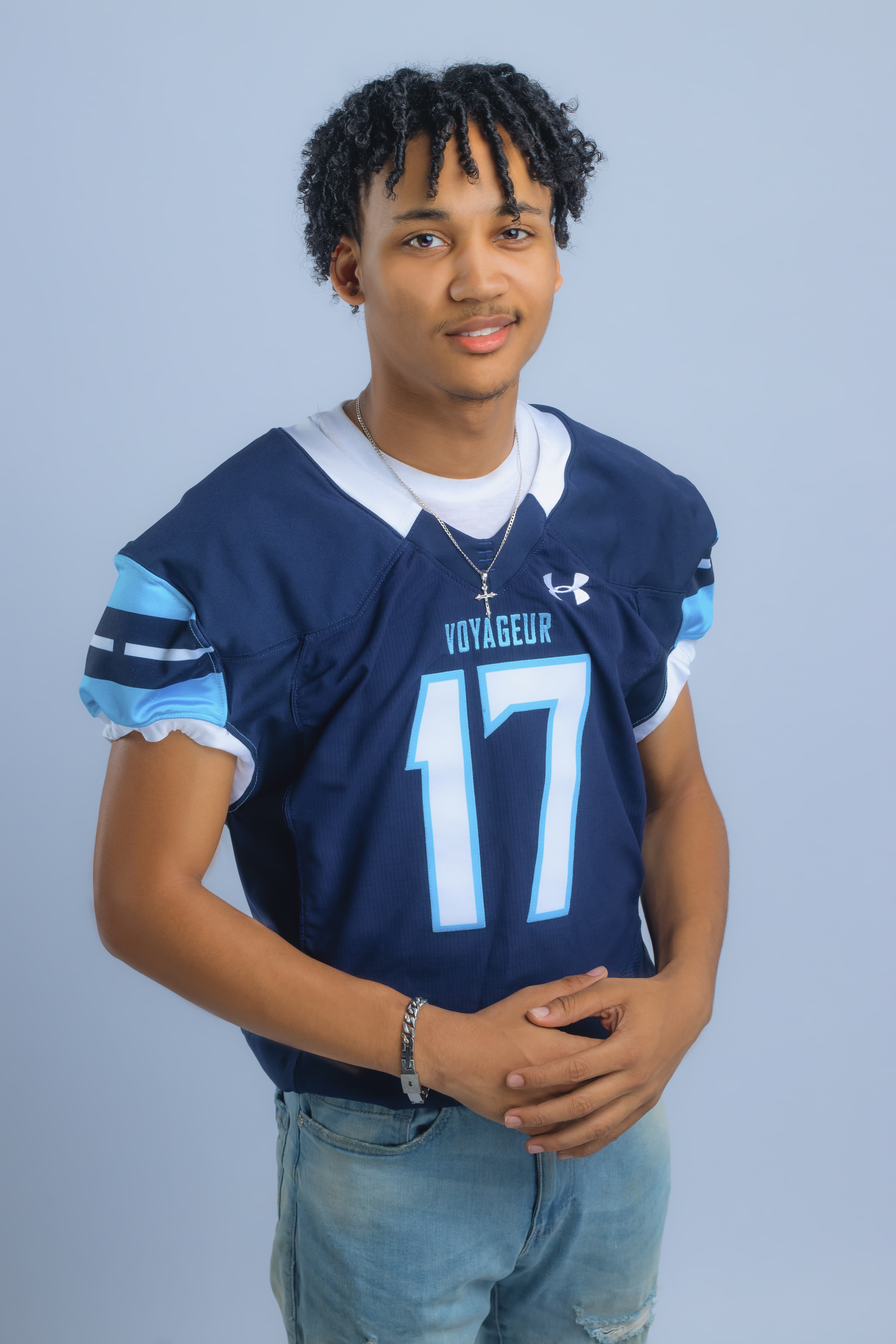 Smiling young man with curly hair wearing a navy blue Voyageur football jersey number 17.